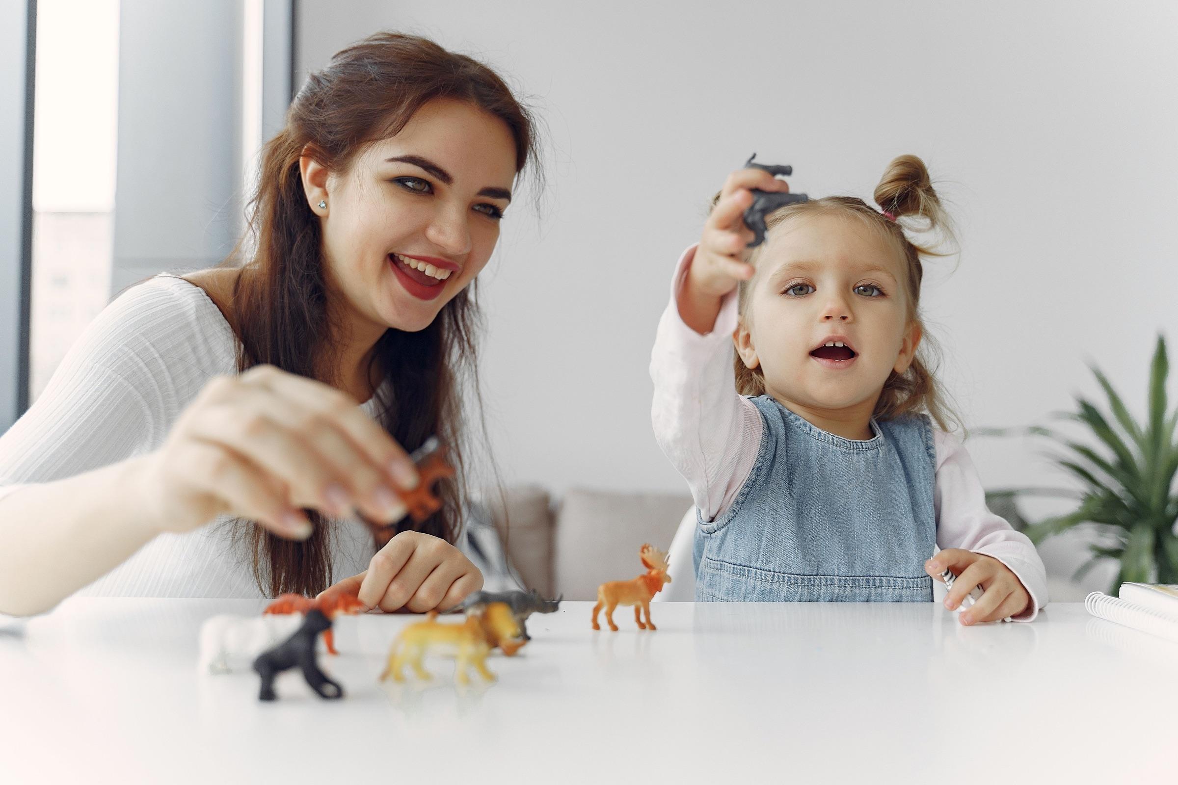 An adult and child playing with toy animals together