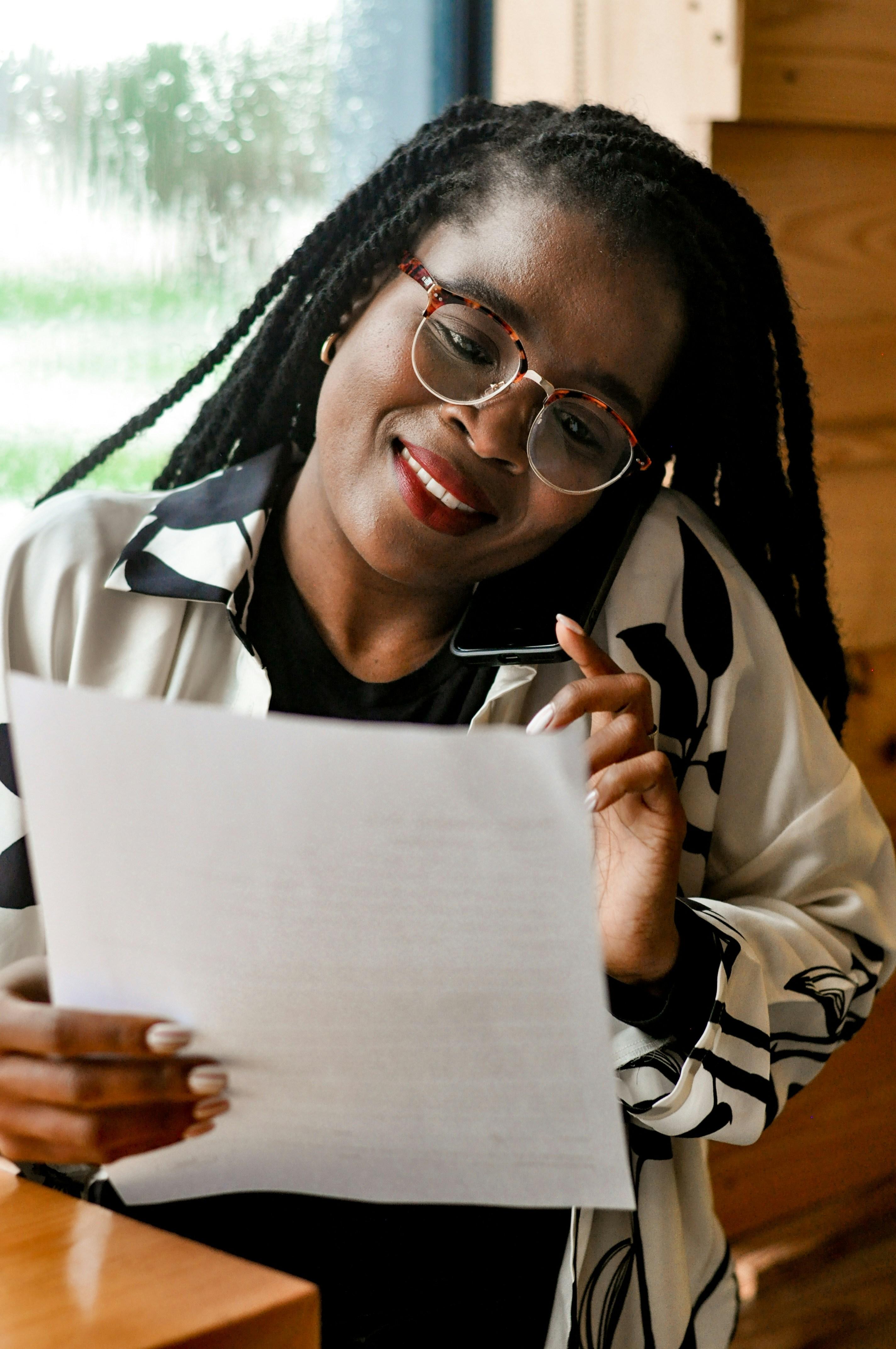 A woman speaks on the phone while reviewing a paper.