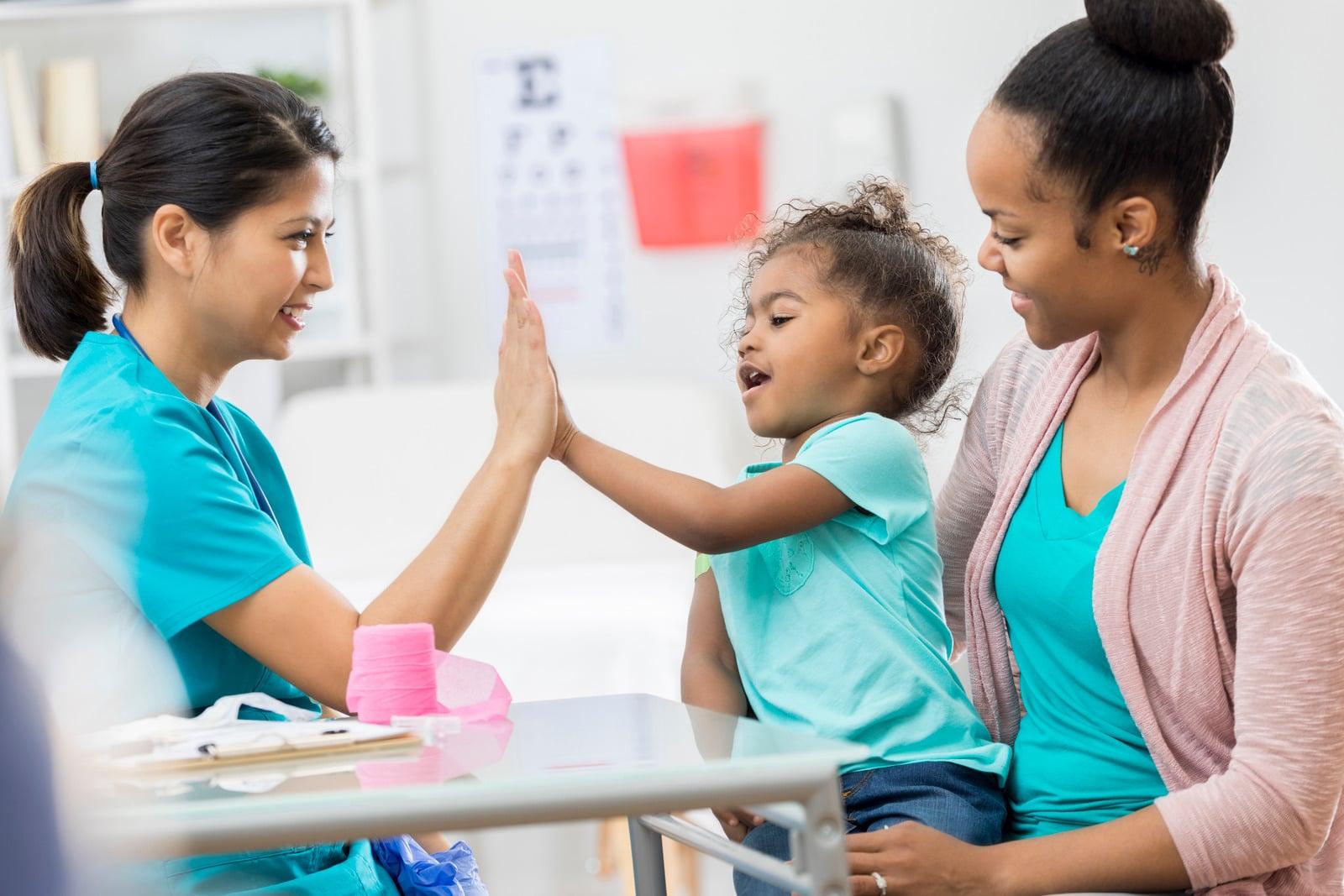 An adult and child sharing a high five in a pediatric care room